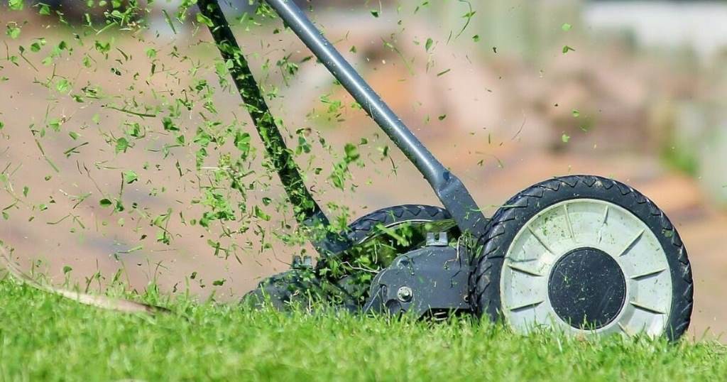 Rusty lawn mower blade clogged with wet grass clippings